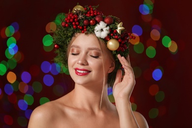 Beautiful young woman wearing Christmas wreath on blurred background. Bokeh effect