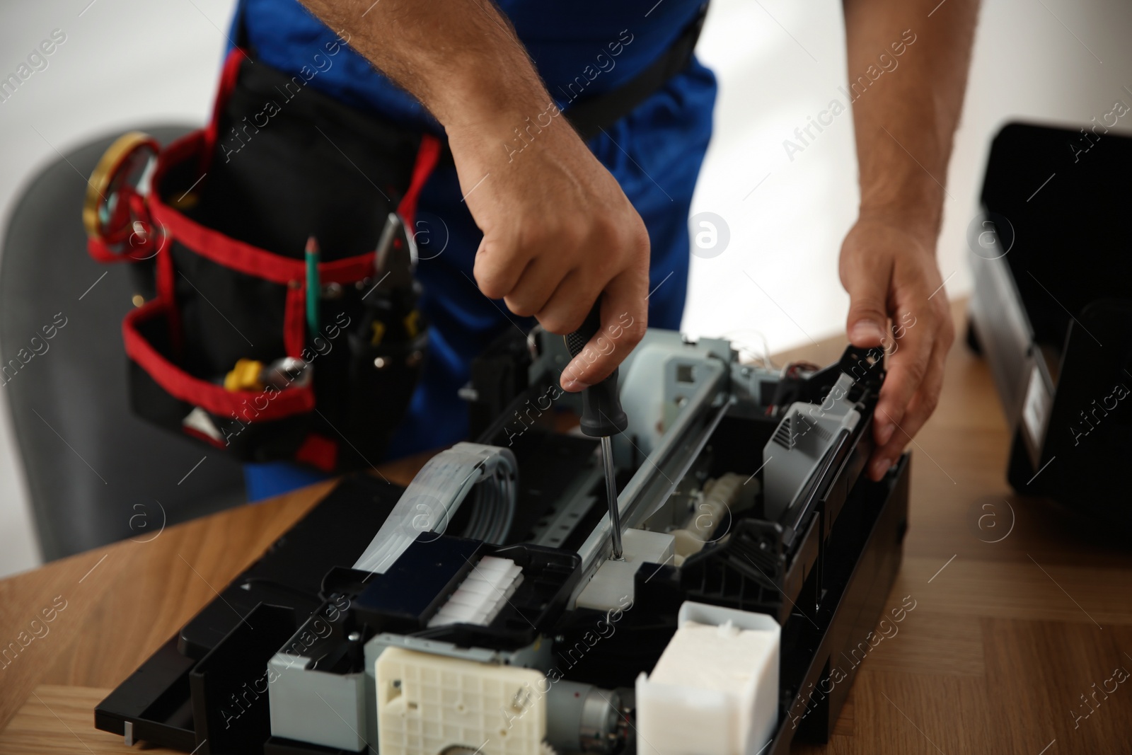 Photo of Repairman with screwdriver fixing modern printer indoors, closeup