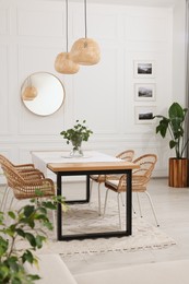 Stylish dining room with cozy furniture, mirror and plants