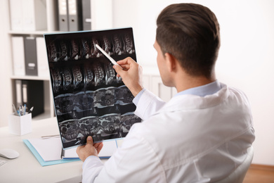 Orthopedist examining X-ray picture at desk in clinic