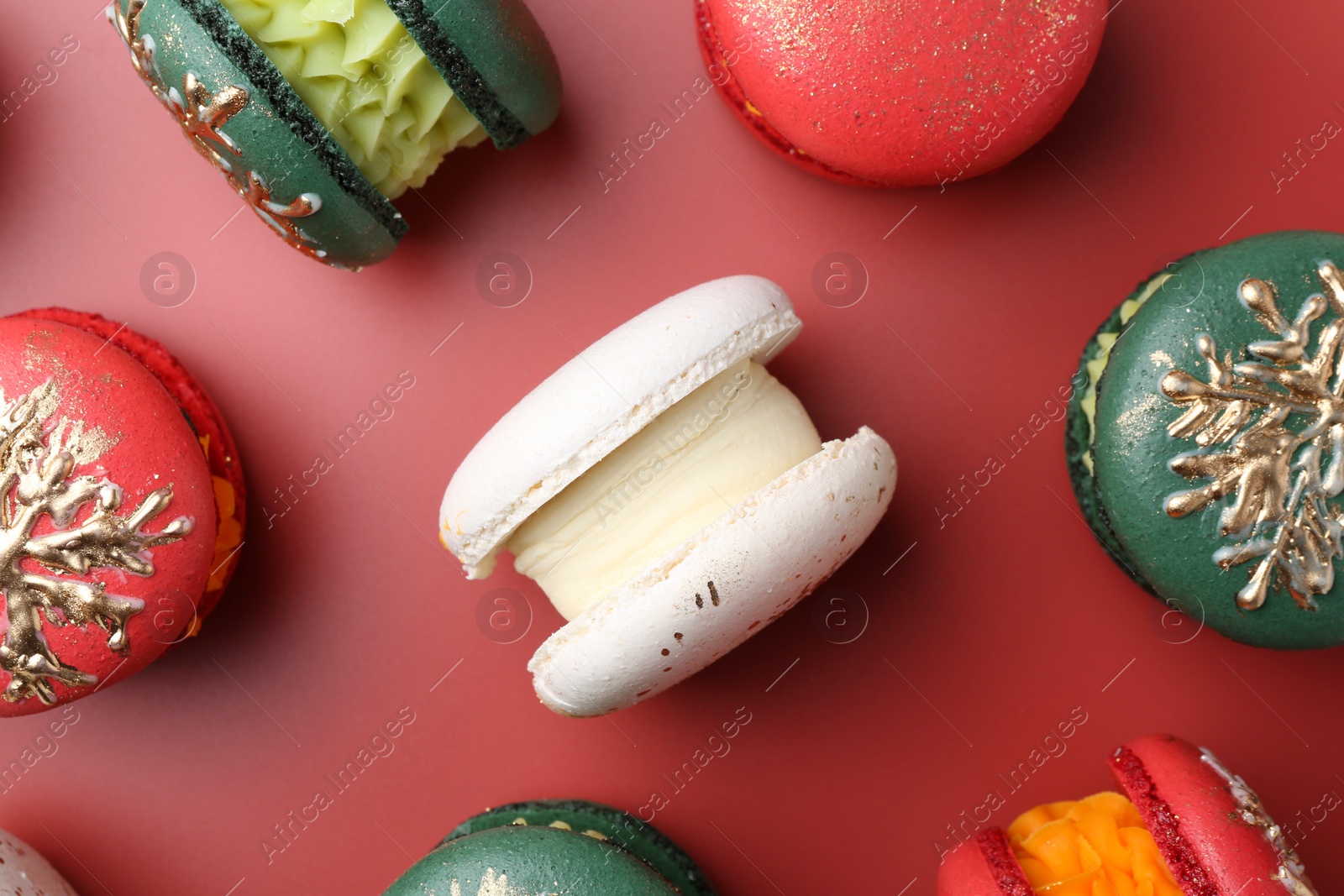 Photo of Beautifully decorated Christmas macarons on red background, flat lay