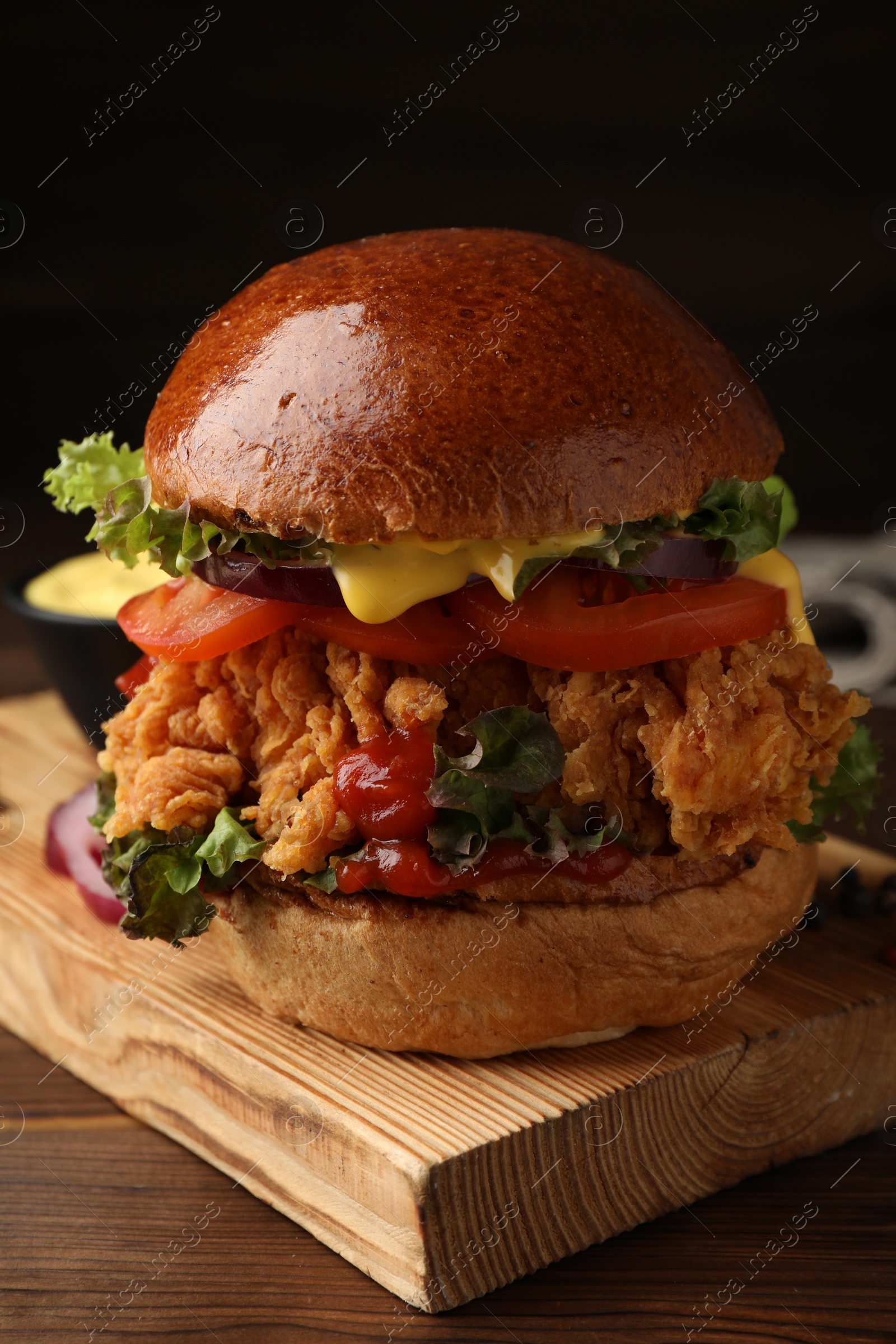 Photo of Delicious burger with crispy chicken patty on wooden table, closeup