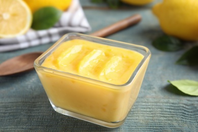 Delicious lemon curd in bowl on wooden table, closeup