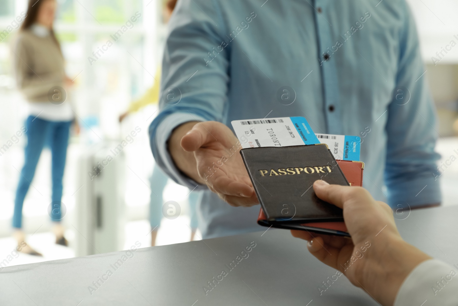 Photo of Agent giving passports and tickets to man at check-in desk in airport, closeup