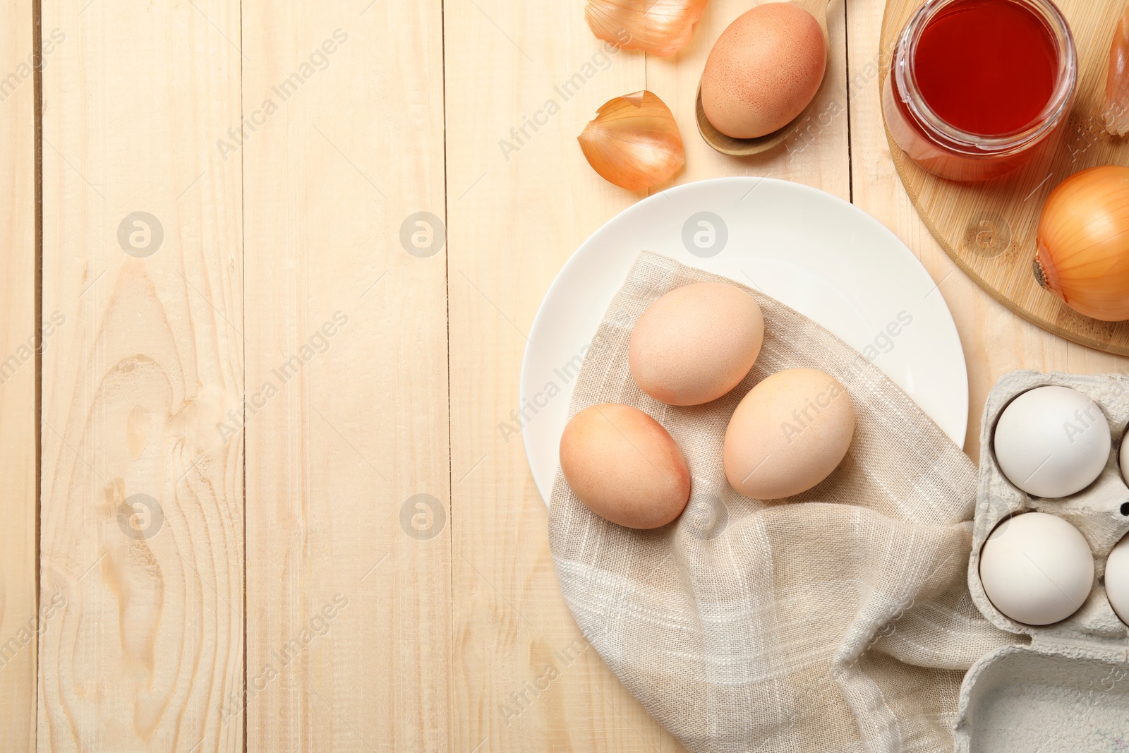 Photo of Easter eggs painted with natural dye and onion on wooden table, flat lay. Space for text