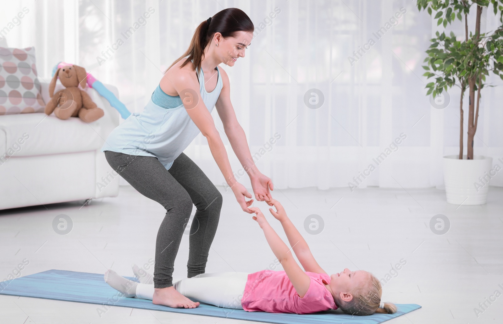 Photo of Woman doing fitness exercises with daughter at home