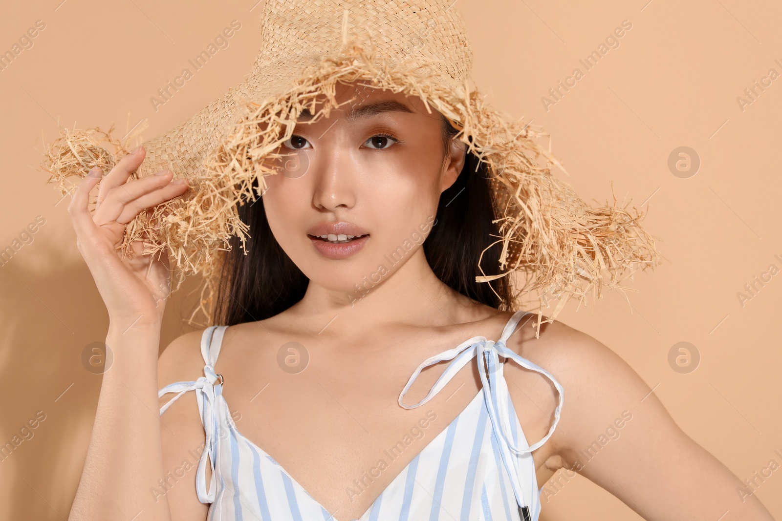 Photo of Beautiful young woman in straw hat on beige background