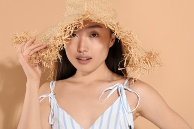 Photo of Beautiful young woman in straw hat on beige background