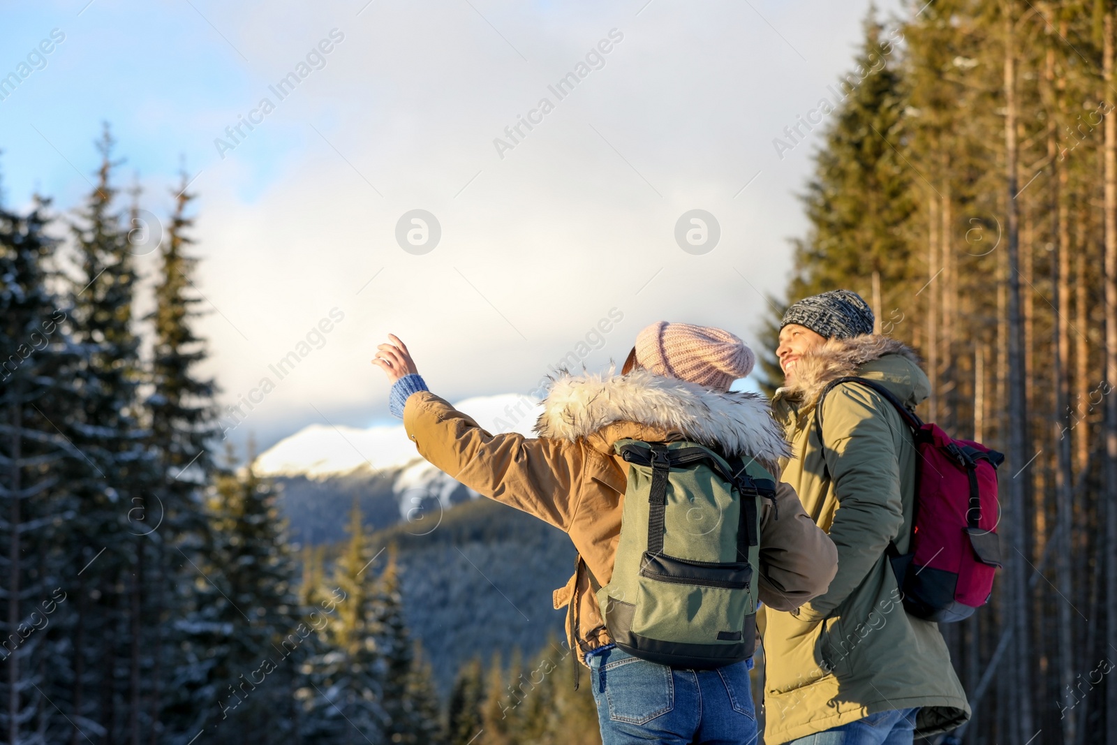 Photo of Couple with backpacks enjoying mountain view during winter vacation