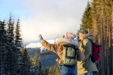 Couple with backpacks enjoying mountain view during winter vacation