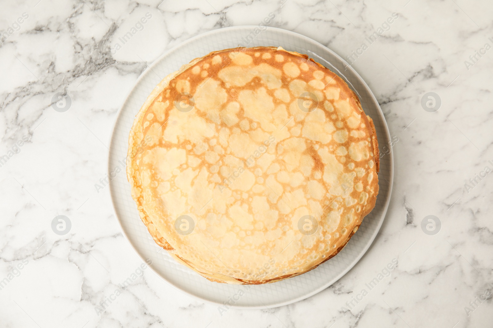 Photo of Stack of fresh thin pancakes on white marble table, top view