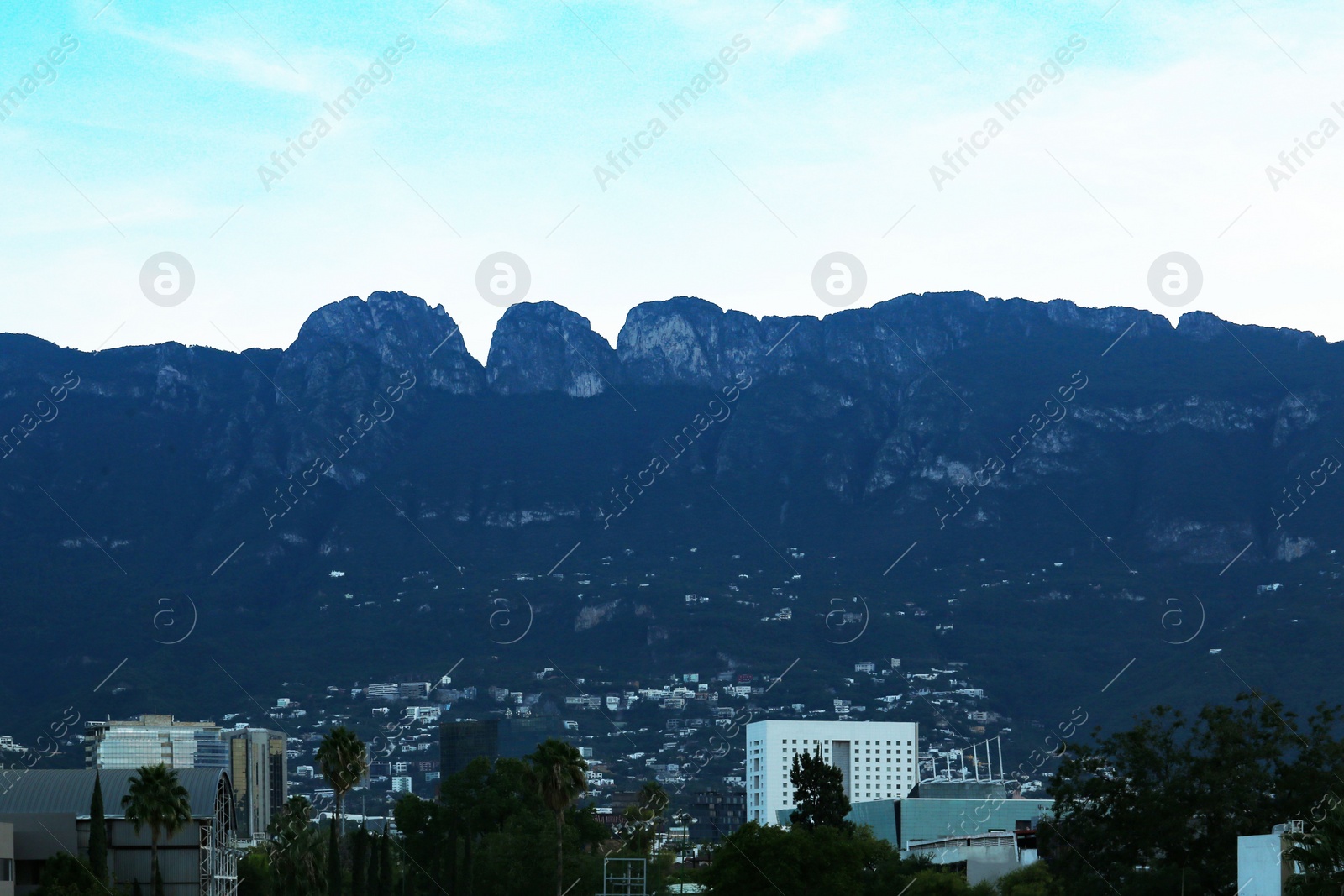 Photo of Picturesque view of mountains and city with skyscrapers at evening