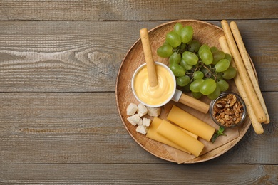 Pot of tasty cheese fondue and products on wooden table, top view. Space for text