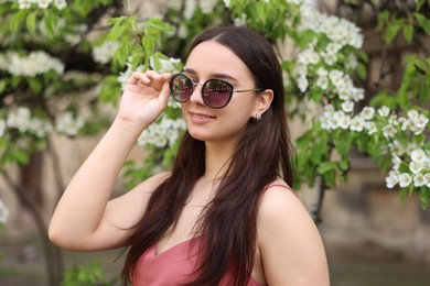 Photo of Beautiful woman in sunglasses near blossoming tree on spring day