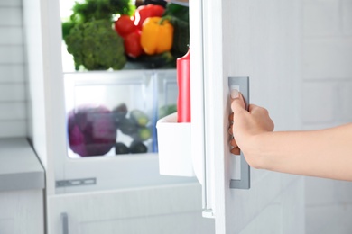 Woman opening refrigerator full of products, closeup