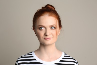 Photo of Candid portrait of happy red haired woman on beige background
