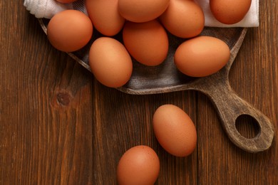 Raw brown chicken eggs on wooden table, flat lay. Space for text