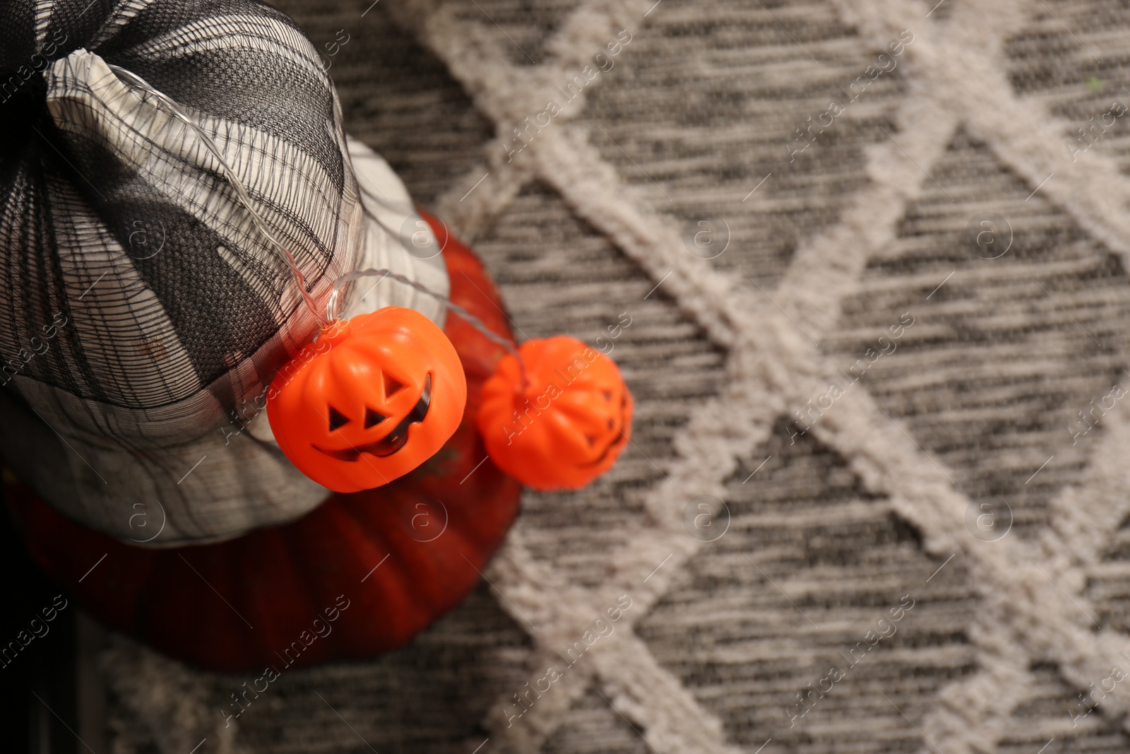 Photo of Jack-o'-lantern lights on color surface, top view with space for text. Halloween decorations