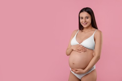 Beautiful pregnant woman in stylish comfortable underwear on pink background, space for text