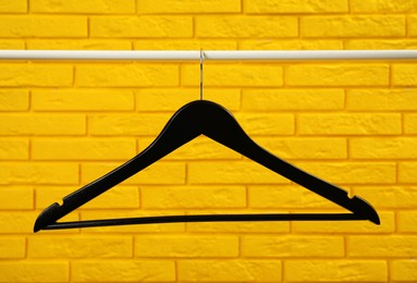 Photo of Wardrobe rack with black hanger near yellow brick wall