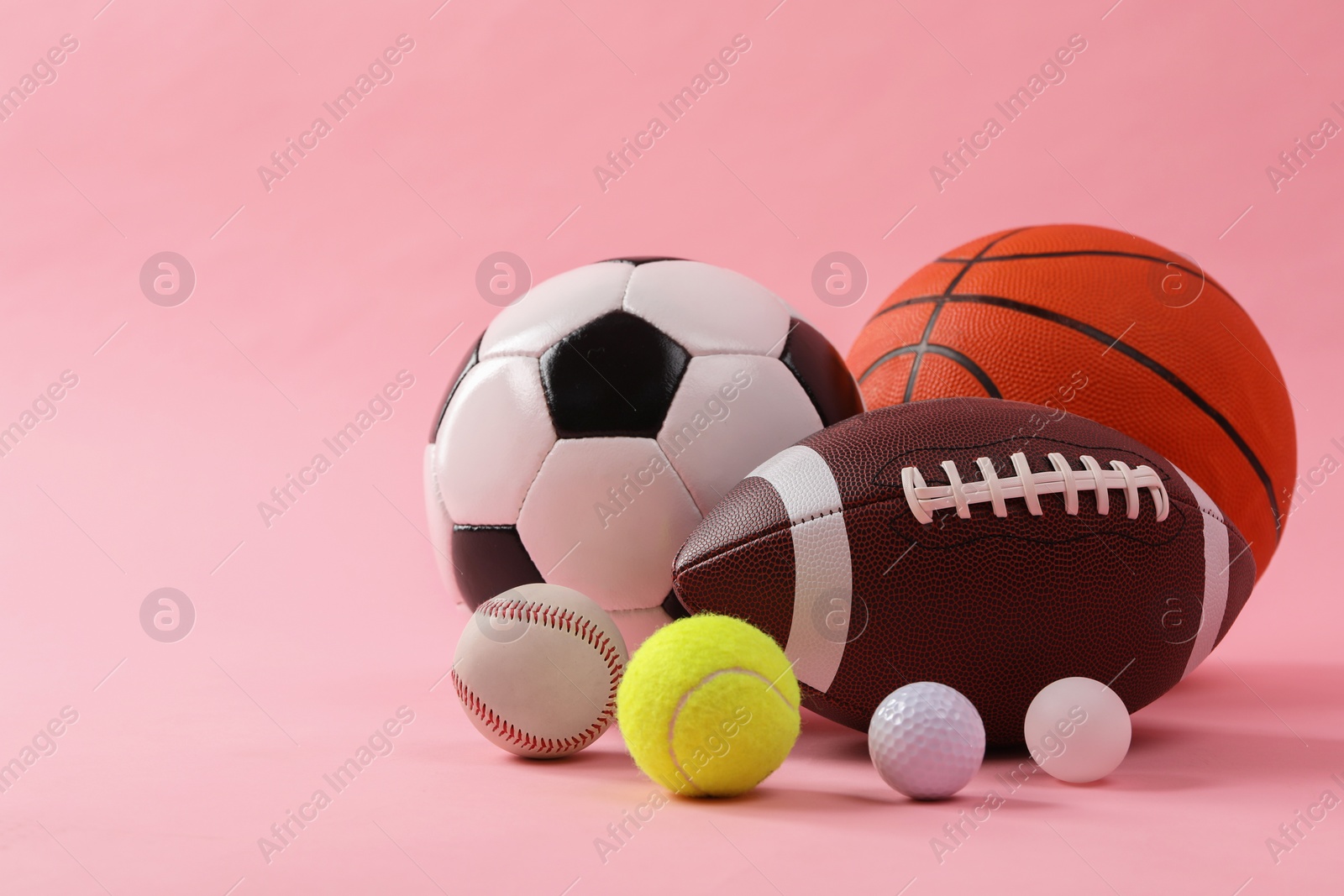 Photo of Many different sports balls on pink background, space for text