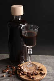 Photo of Bottle of coffee liqueur, shot glass and beans on light grey table