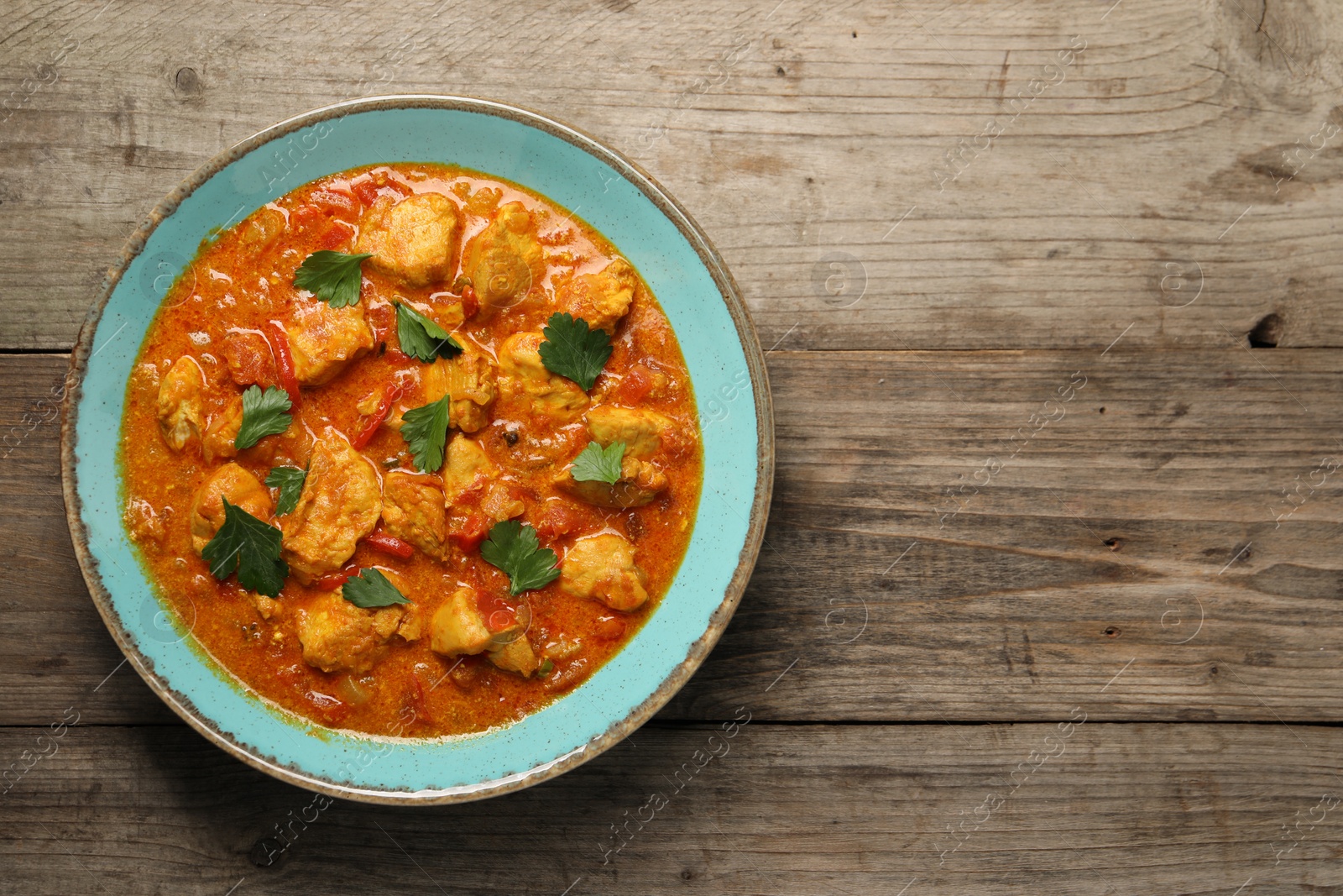 Photo of Delicious chicken curry on wooden table, top view. Space for text