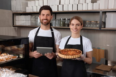 Photo of Sellers with tablet and freshly baked quiche in bakery shop