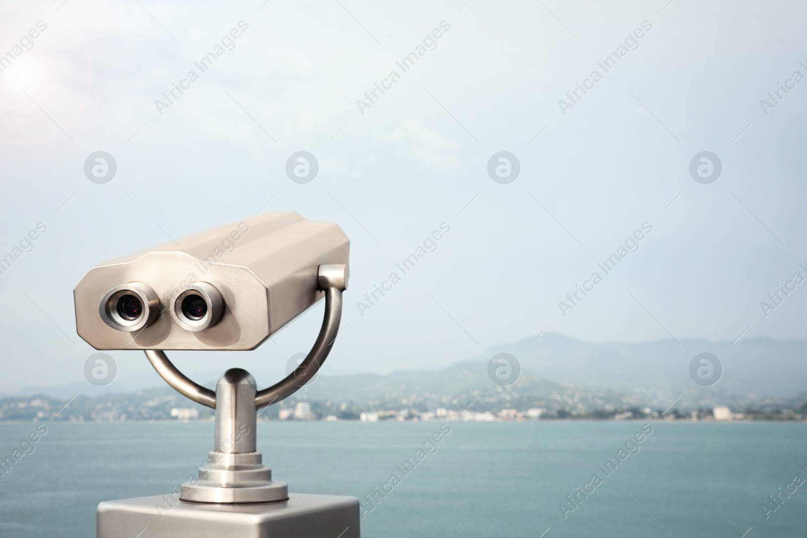 Photo of Metal tower viewer installed near sea, space for text. Mounted binoculars