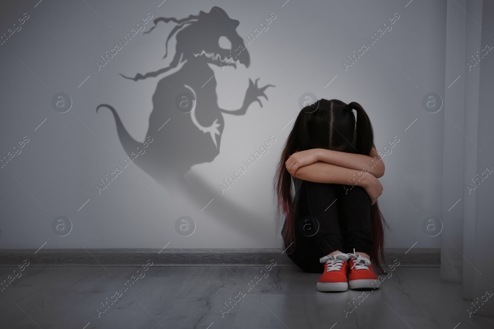 Image of Shadow of monster on wall and scared little girl in room