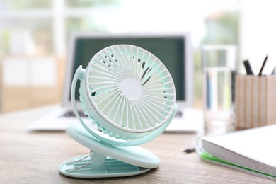 Photo of Modern portable fan on wooden table in office. Summer heat