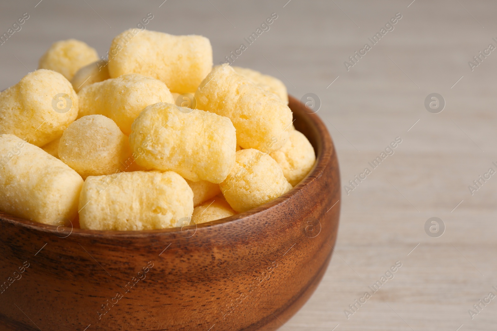 Photo of Bowl of corn sticks on wooden table, closeup