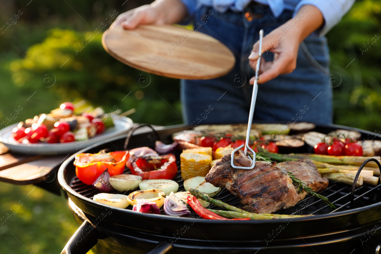 Photo of Woman cooking meat and vegetables on barbecue grill outdoors, closeup