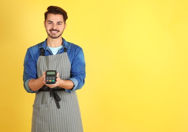 Waiter with payment terminal on color background. Space for text