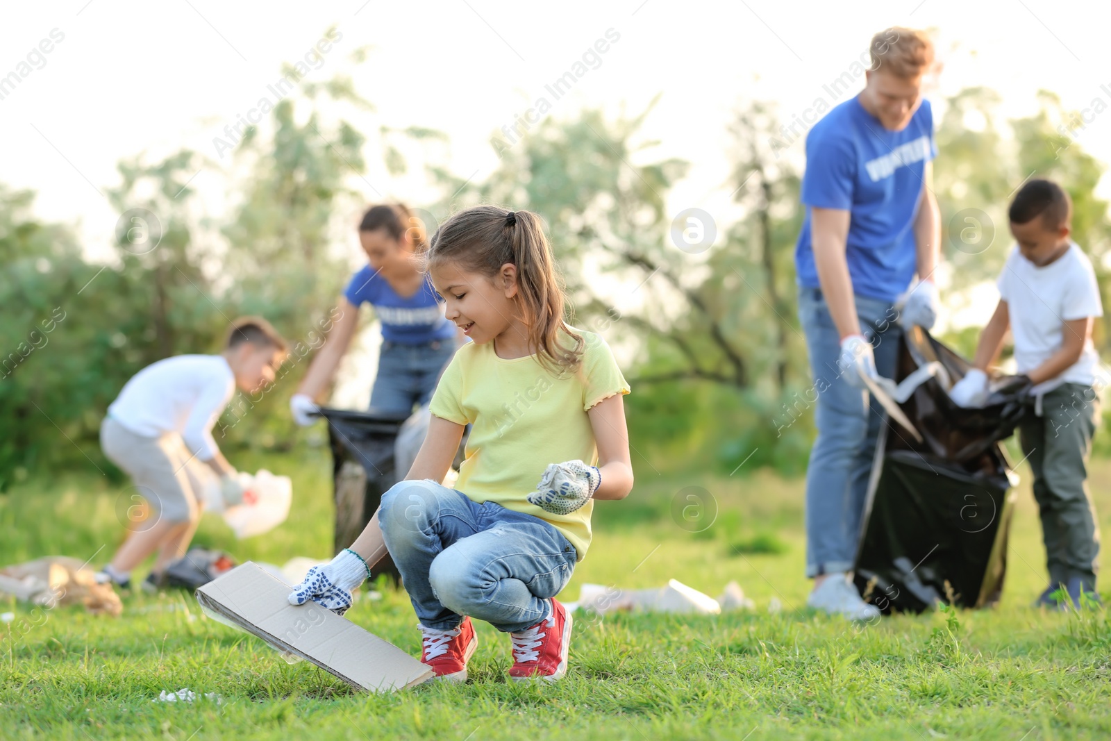 Photo of Little girl collecting trash in park. Volunteer project