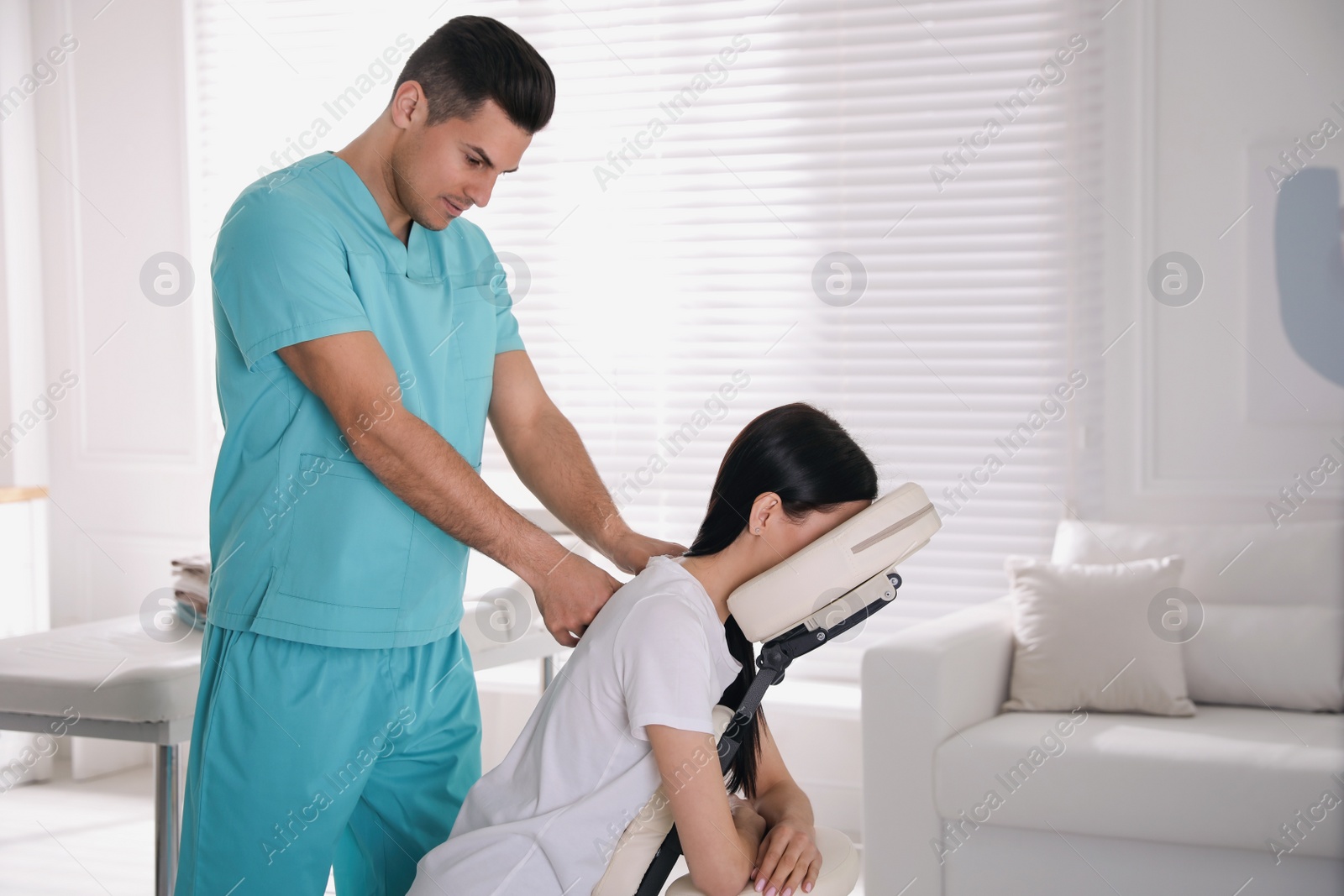 Photo of Woman receiving massage in modern chair indoors