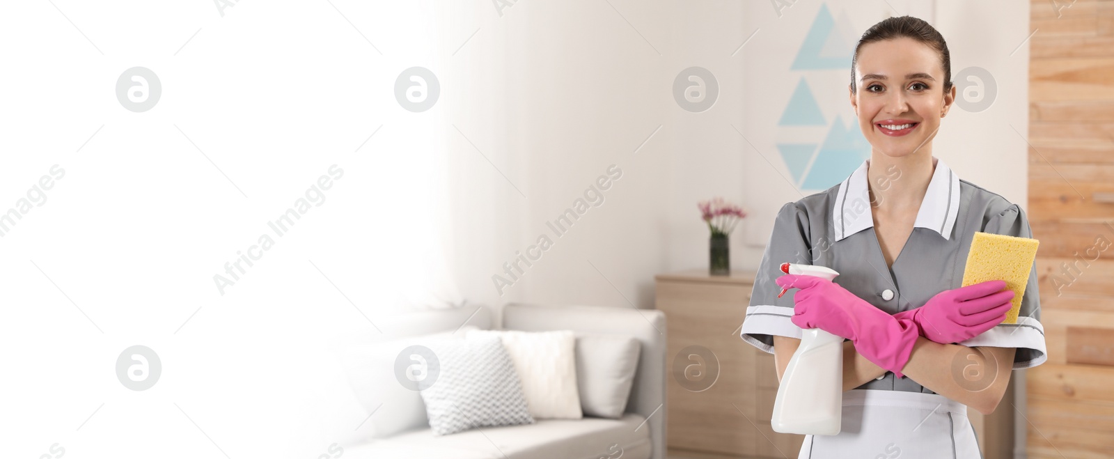 Image of Portrait of young chambermaid with cleaning supplies in hotel room, space for text. Banner design