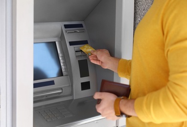 Young man using modern cash machine outdoors, closeup