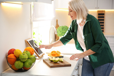 Woman with tablet cooking at counter in kitchen