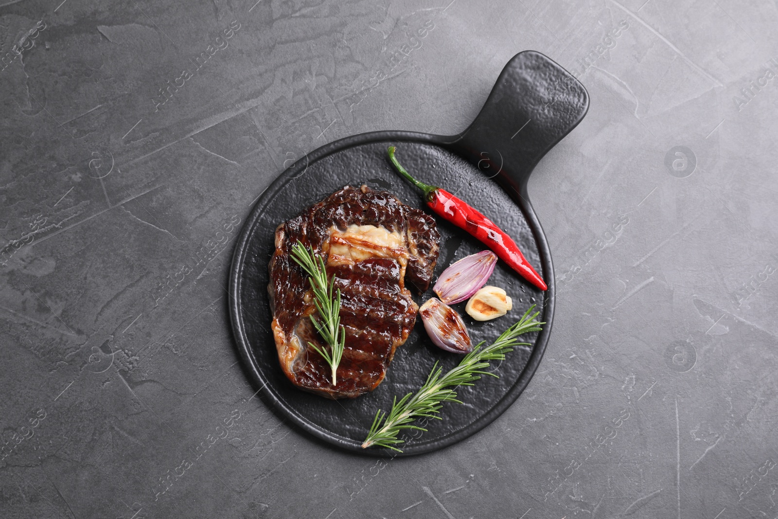 Photo of Delicious grilled beef meat, rosemary and spices on gray textured table, top view