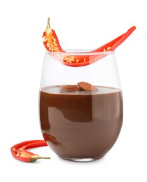 Photo of Glass of hot chocolate with chili pepper and almonds on white background