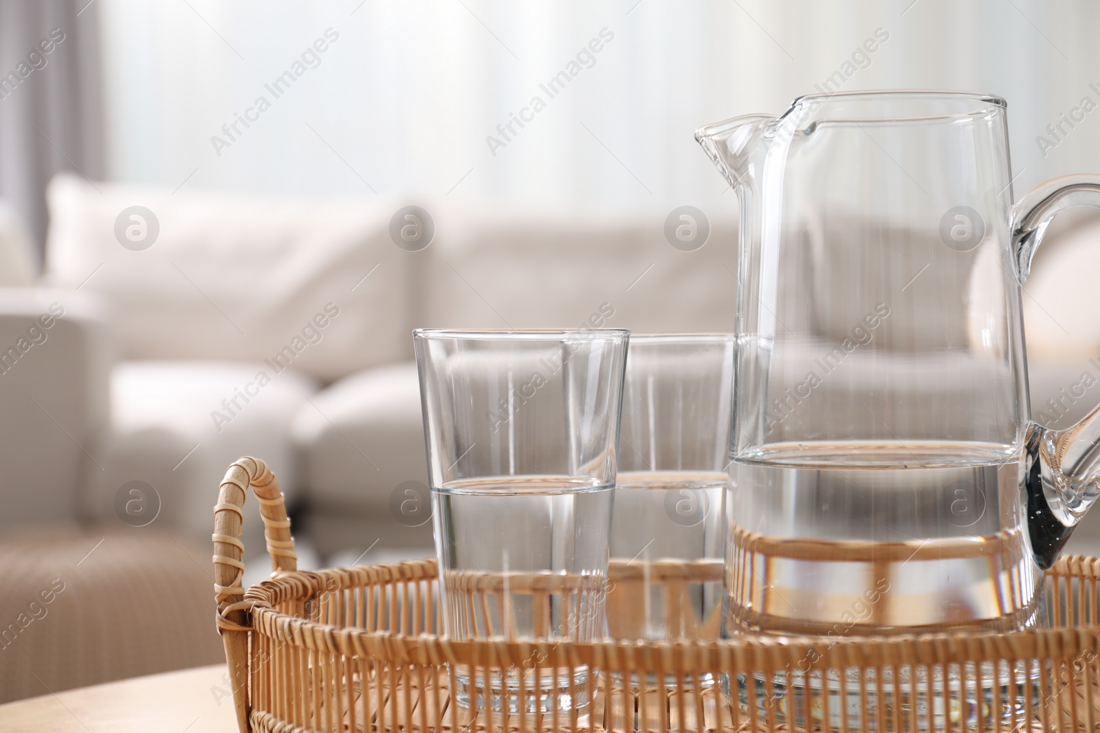 Photo of Jug and glasses with clear water on blurred background, closeup. Space for text