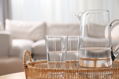 Jug and glasses with clear water on blurred background, closeup. Space for text