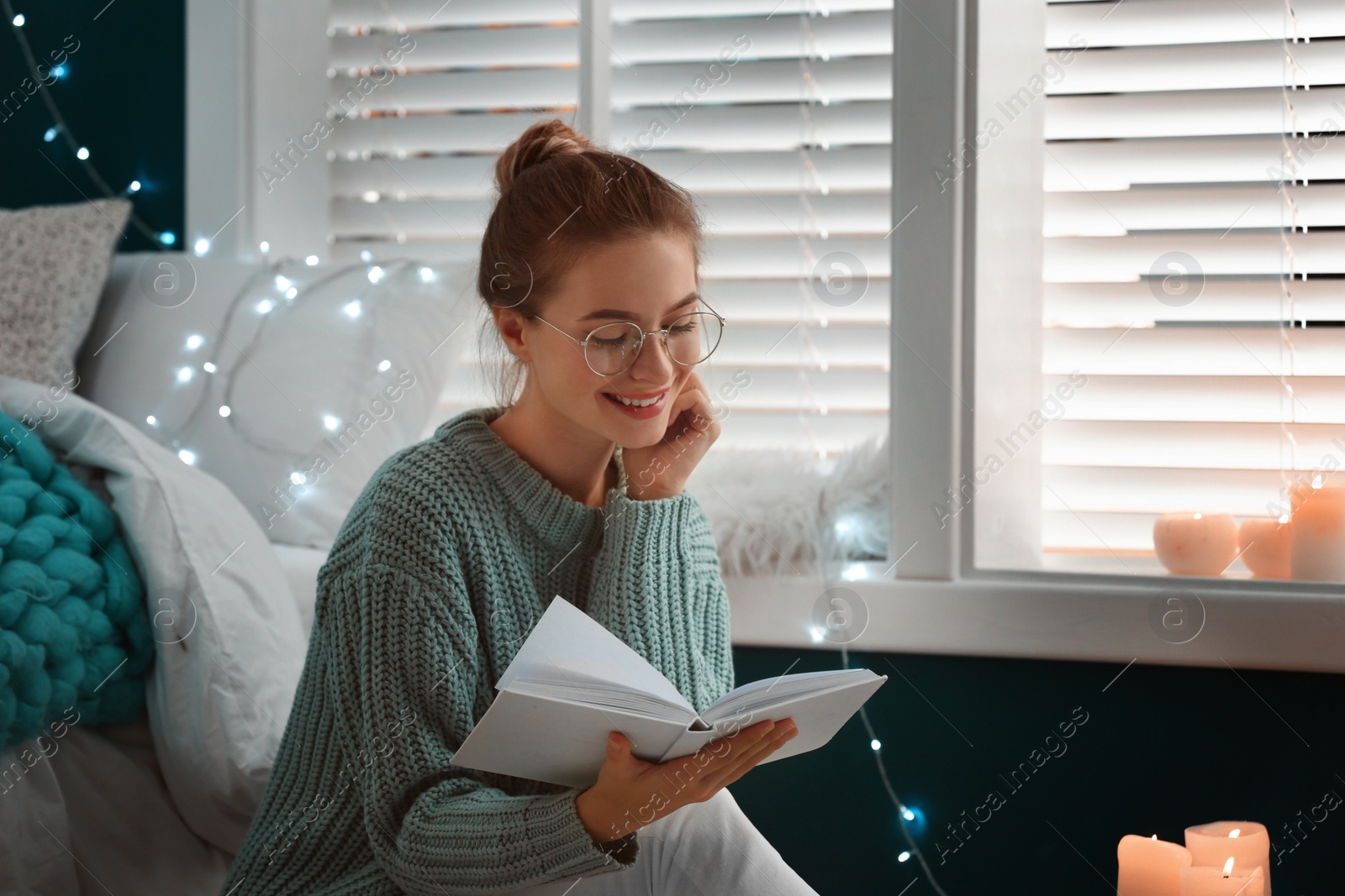 Photo of Young woman reading book at home. Cozy winter