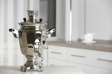 Photo of Metal samovar on grey table in kitchen, space for text. Russian tea culture