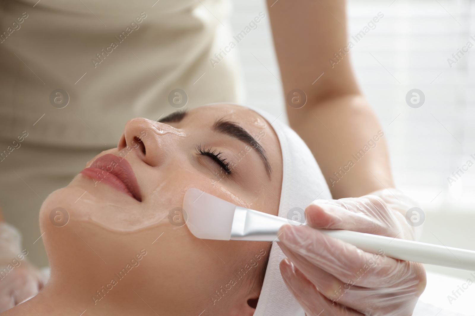 Photo of Young woman during face peeling procedure in salon