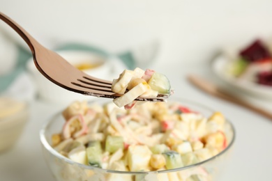 Photo of Fork with delicious crab stick salad over glass bowl, closeup