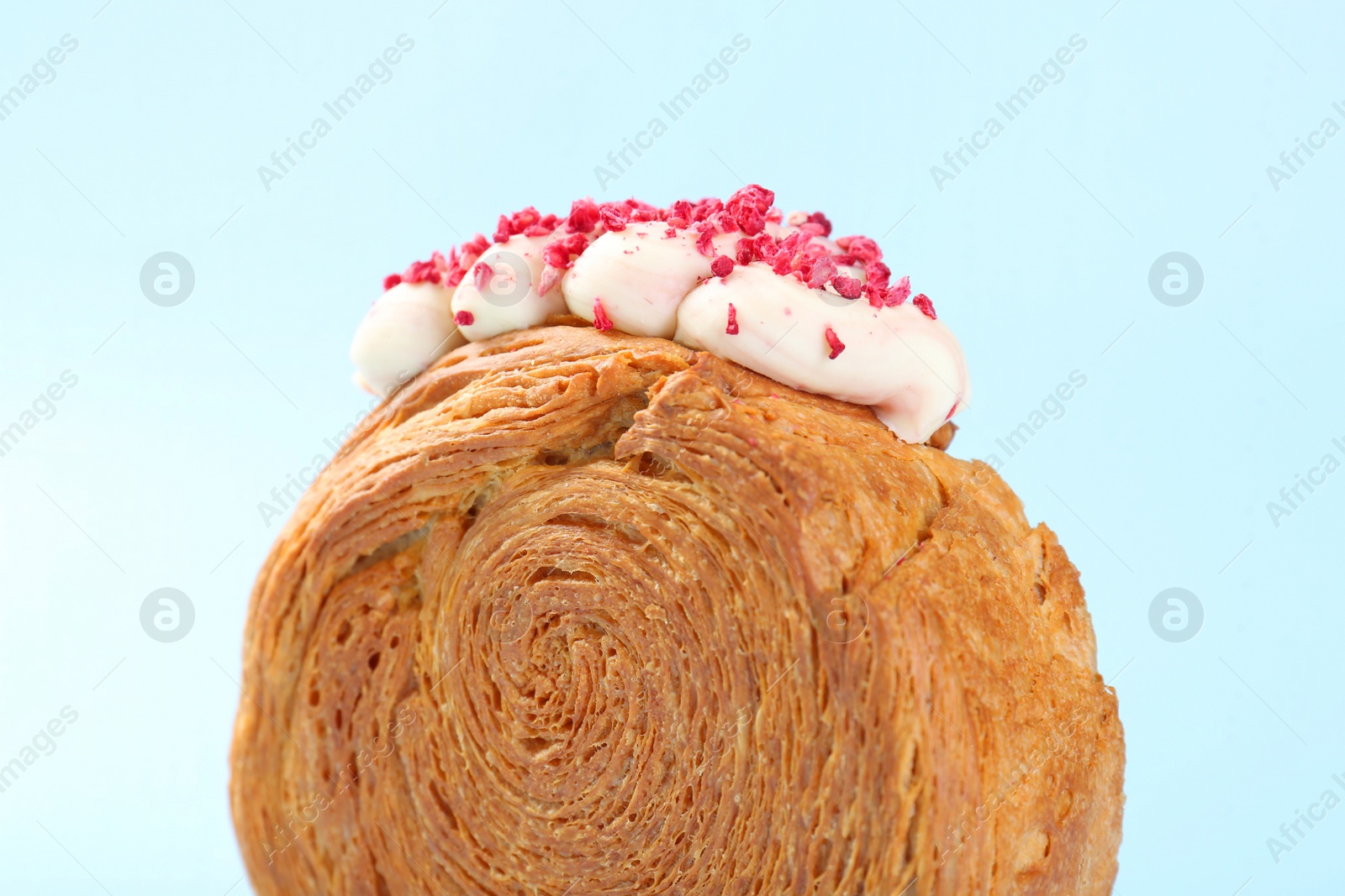 Photo of One supreme croissant with cream on light blue background, closeup. Tasty puff pastry