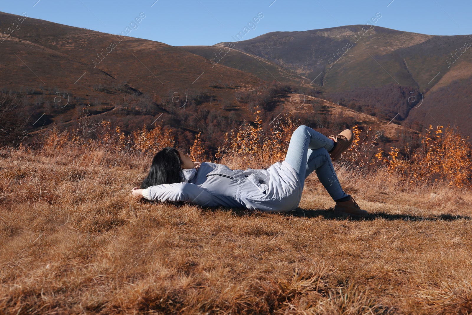 Photo of Woman in warm clothes relaxing on mountain slope