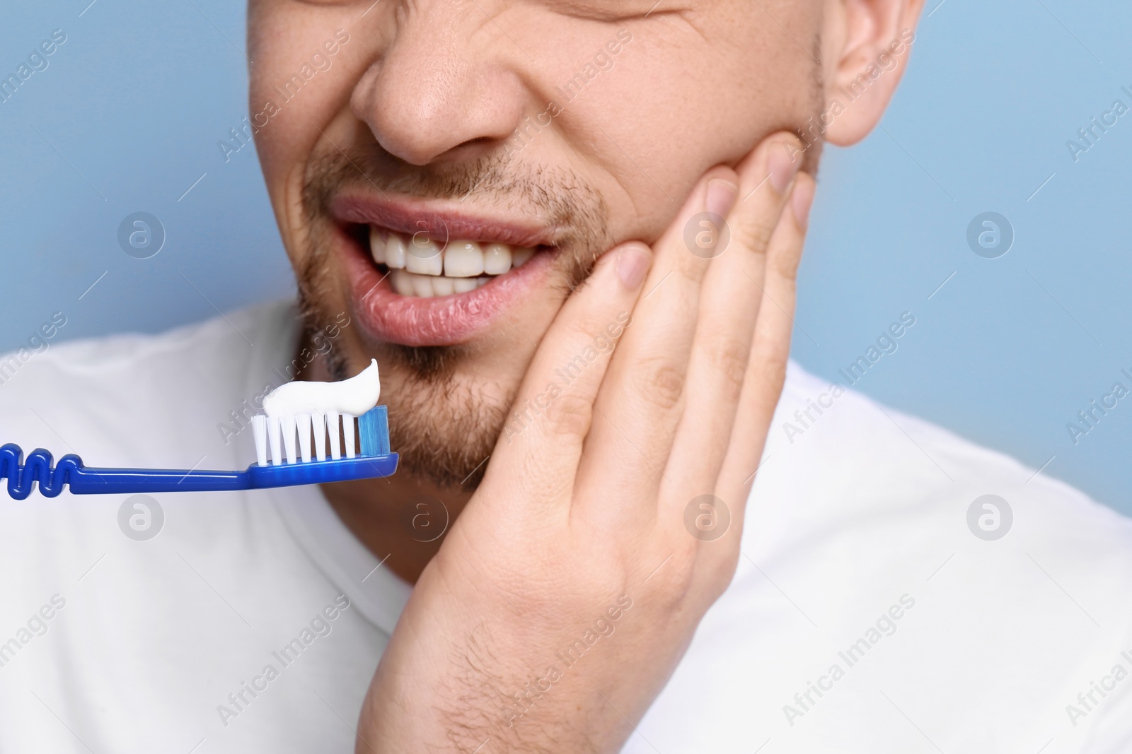 Photo of Young man suffering from toothache on grey background